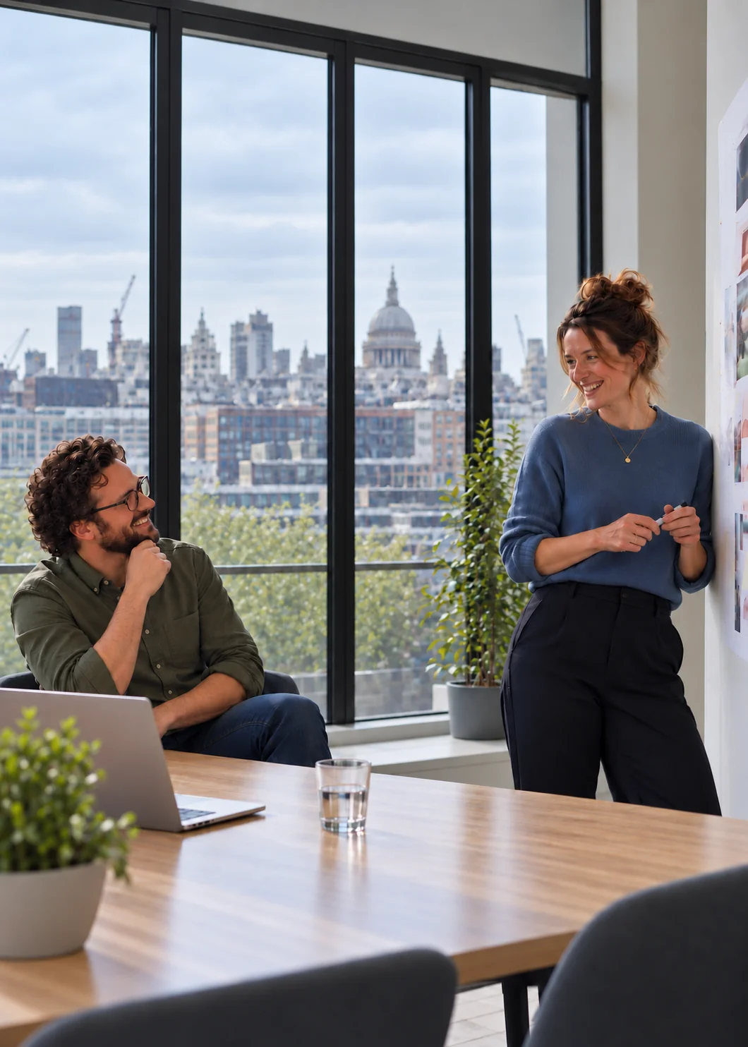 Two colleagues talking in a bright meeting room overlooking the city